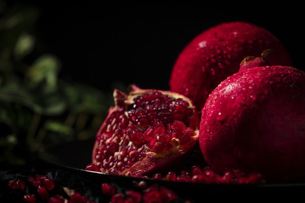 Sliced pomegranate with protruding seeds in a dark atmosphere