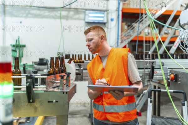 Industrial worker wearing safety vest checking quality of bottles on a beverage factory automated conveyor belt, ensuring efficient labeling and packaging process
