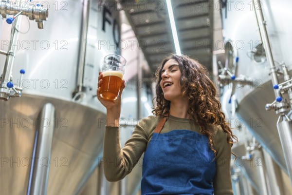 Woman tasting craft beer for quality control, evaluating the quality of the beverage in a modern brewing facility, checking the flavor and appearance of the industrial product