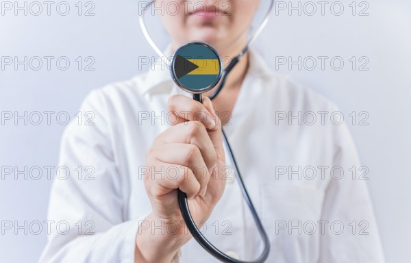 Female doctor holding stethoscope with Bahamas flag. National health system of Bahamas