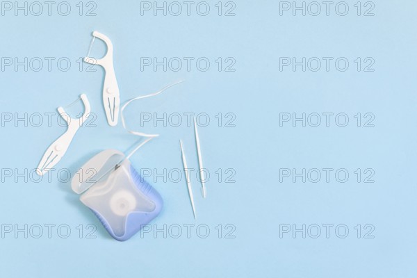 Dental floss and toothpicks on blue background with copy space. Oral hygiene products