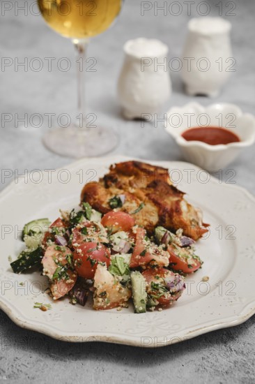 A fresh salad made with tomatoes, cucumbers, and herbs is served alongside grilled chicken