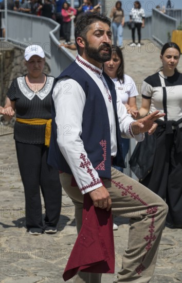 Man in traditional traditional costume performing movement, surrounded by people, folklore, Tatev, Tatev, Syunik province, Syunik, Armenia