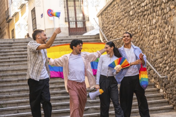 Diverse friendship group celebrating lgbtq plus pride and equality during a parade, walking down urban stairs, holding a rainbow flag, fan, megaphone, and small flag, showing joy and community