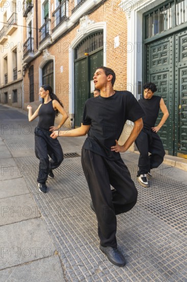 Group of young modern dancers performing an energetic routine on a city street, expressing movement and passion while practicing their art form in an urban environment