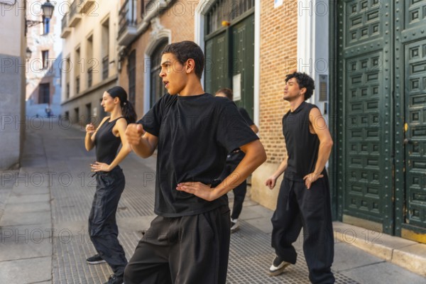 Young men and women in black clothing performing a synchronized dance routine on a cobblestone alley in a european city, expressing artistic freedom and urban culture