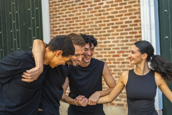 Diverse group of young adults laughing and embracing outdoors, enjoying casual summertime hangout and genuine friendship against an urban brick wall backdrop, carefree and joyful