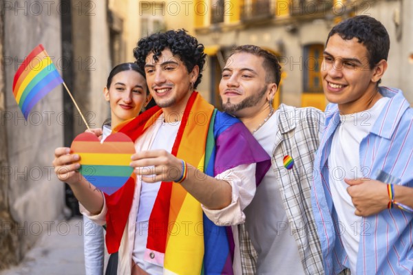 Young friends proudly displaying rainbow heart, flag and shawl at an outdoor pride celebration, smiling and united in love, inclusion and multiracial queer community support