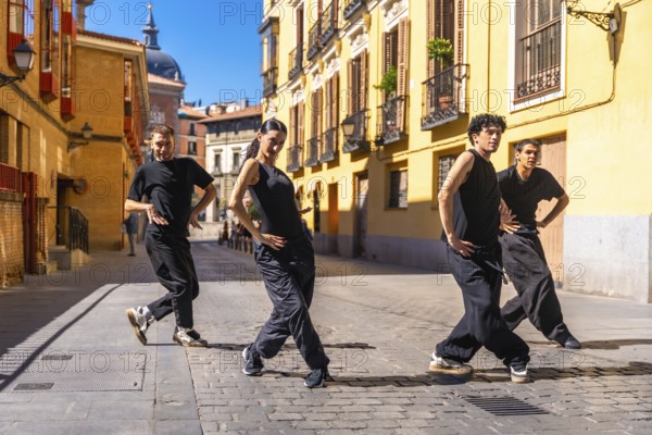 Group of urban dancers in black clothes performing a contemporary dance routine on a cobbled street in madrid, spain, showcasing artistic movement and urban culture