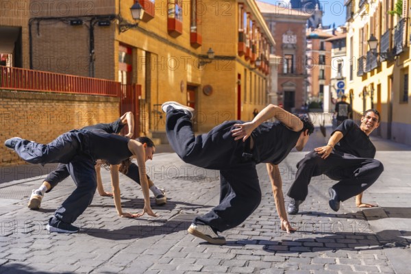 Group of young and energetic hip hop dancers moving in a synchronized street performance on a cobbled stone street in an old european city, showcasing urban culture and freedom of expression