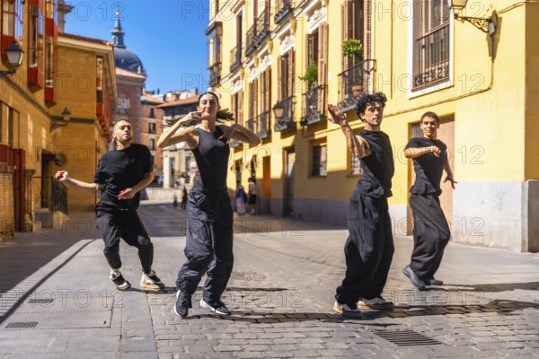 Four young dancers expressing themselves through contemporary dance, performing a street choreography on a sunny day in an old cobblestone street in madrid, spain
