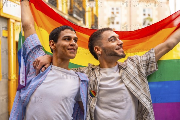 Two smiling men embracing and proudly displaying the vibrant rainbow flag, symbolizing lgbtq plus rights, love, and diversity during a public demonstration