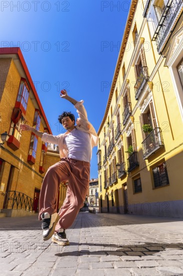 Man dancing energetically on a sunny cobblestone street in madrid, showcasing urban style and contemporary movement, freedom, joy and confident street performance