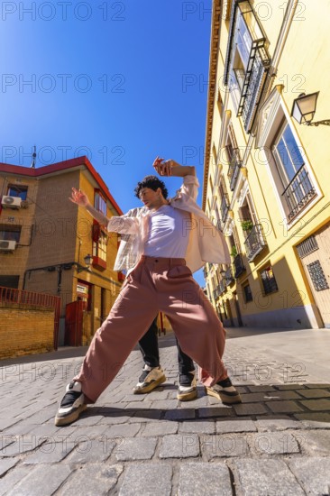 Young man actively dancing a contemporary urban street performance, expressing freedom and vibrant energy on a sunny day in an old city alley with traditional architecture