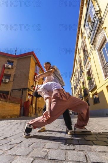 Two skilled dancers engaging in a passionate contemporary performance on a cobblestone street, expressing movement and connection in an urban environment with traditional buildings
