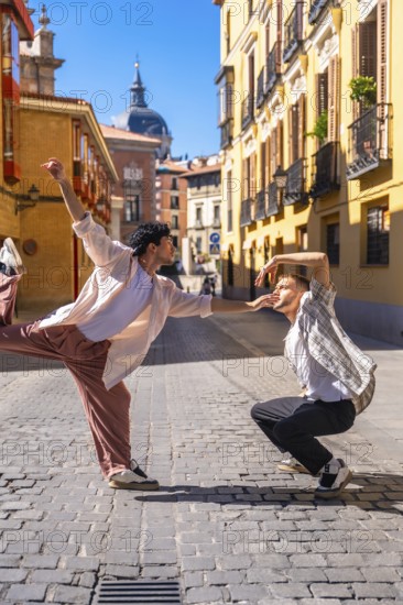 Two young men expressing emotion and movement through a modern dance routine on a cobblestone street, performing in an urban setting with historic architecture