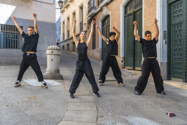 Four young dancers perform synchronized street choreography on an urban street, radiating energy, unity and contemporary style as they express passion, skill and youth culture in daylight