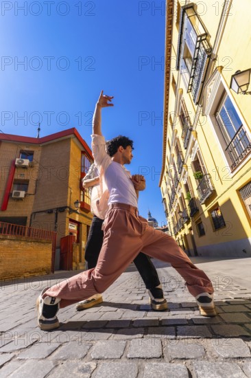 Two young men engaging in an energetic dance performance on a sunny historic cobblestone street, expressing freedom and movement while showcasing urban culture