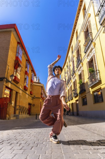 Young man creating art with his body, dancing ballet street style in an urban environment, expressing freedom and joy in the middle of a city street on a sunny day