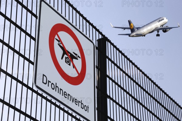 (Photomontage) Fence with sign DROHNENVERBOT, in the background a Lufthansa aeroplane taking off
