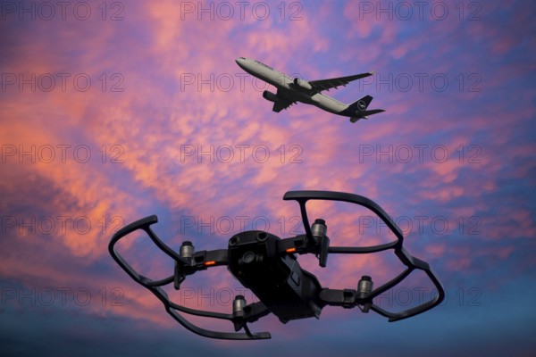 (Photomontage) Close-up of a drone in the evening sky, a Lufthansa aircraft in the background