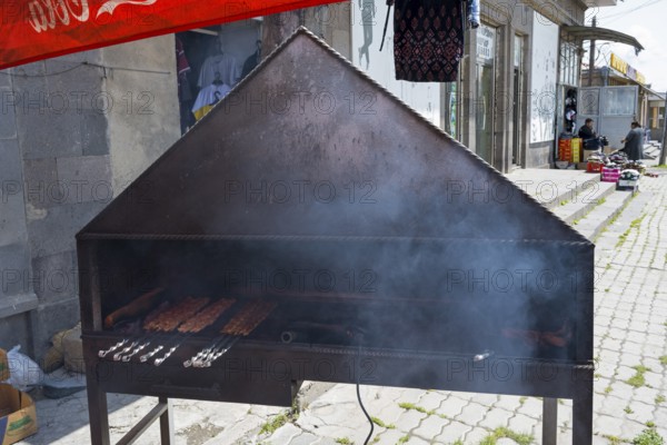 Outdoor barbecue with meat skewers, smoke rising, on a metal rack, minced meat on a spit, Martuni, Gegharkunik province, Armenia