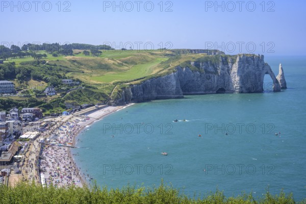 View of the village with beach and rock arch behind it Falaise d'Aval, Étretat, Département Seine-Maritime, France