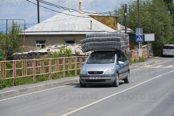 A car carrying goods on its roof, driving along an urban road, Geghhovit, Geghahovit, Verin Gharanlugh, Gegharkunik province, Armenia