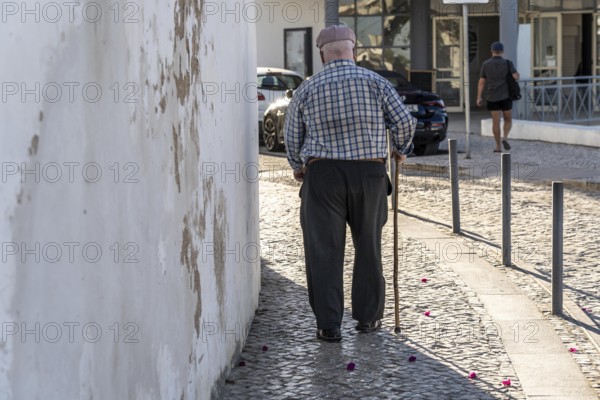Elderly man with walking stick, in the historic centre of Lagos, Algarve, Portugal