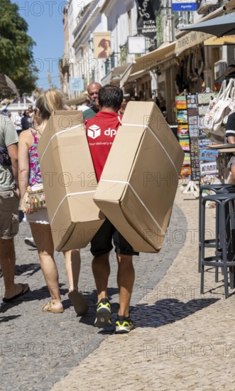 DPD courier, carrying parcels in the historic centre of Lagos, Algarve, Portugal, delivery on foot, pedestrian zone
