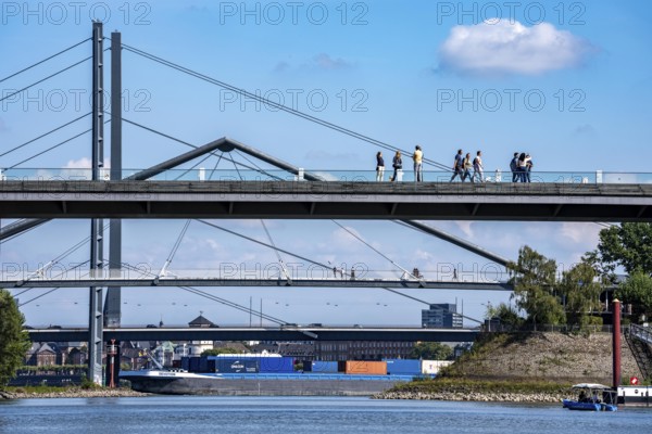 Bridges in Düsseldorf, in the foreground, the pedestrian and cycle bridge over the canal to the inner harbour, media harbour of Düsseldorf, behind it the Rheinknie bridge, road bridge over the Rhine near Düsseldorf, cargo ship, Germany