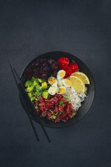 Fresh poke bowl with tuna, avocado, and vegetables served on a black plate