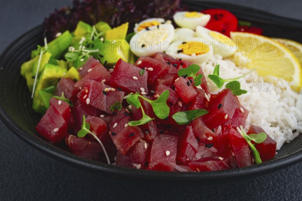 Fresh poke bowl with tuna, avocado, and vegetables served on a black plate