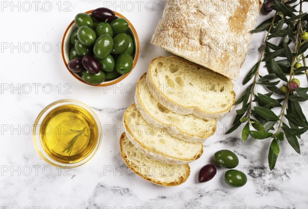 Appetizer, sliced ciabatta bread, with olive oil, green olives, Chalkidiki olives, classic Green green olive, on a marble table, top view, no people