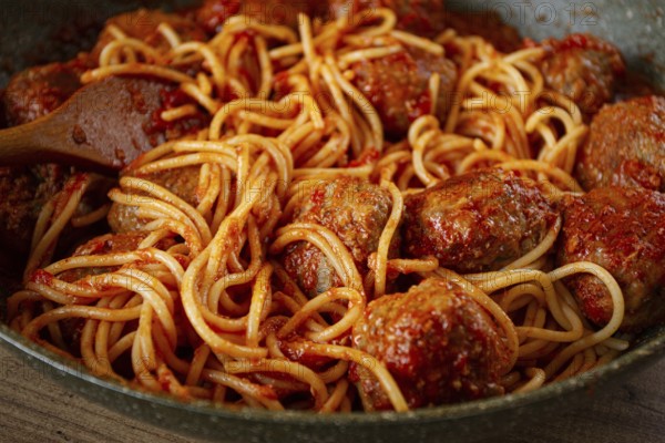Spaghetti with meatballs, in tomato sauce, cooking in a frying pan, no people, homemade