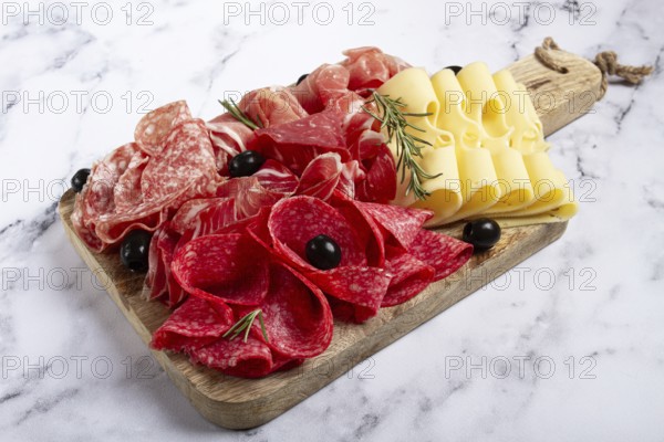 Assorted meat, appetizer, prosciutto, salami and ham, with maasdam cheese and olives, on a wooden board, breakfast, top view, close-up, no people