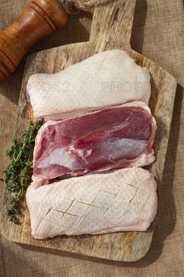 Fresh raw duck breast, on a wooden chopping board, top view, no people
