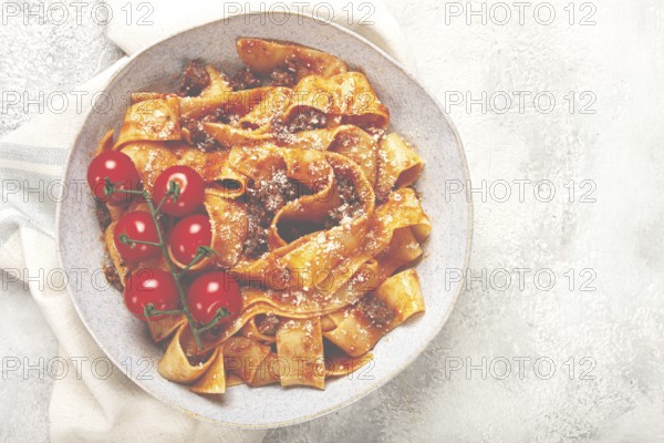 Pappardelle pasta with bolognese sauce, topped with parmesan cheese and cherry branch, homemade, no people