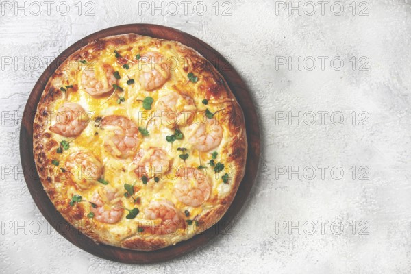 Four cheese pizza with shrimp and fresh microgreens, served on a wooden board, homemade, no people