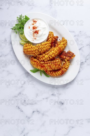 Corn ribs, with cream sauce, spices and lime, appetizer, on a white plate, homemade, no people