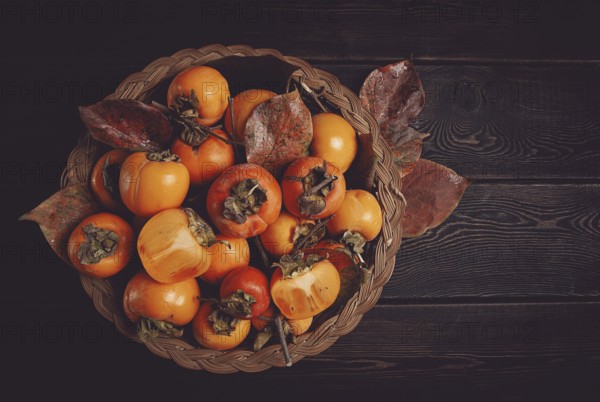 Fresh persimmon in a basket, with leaves, top view, no people