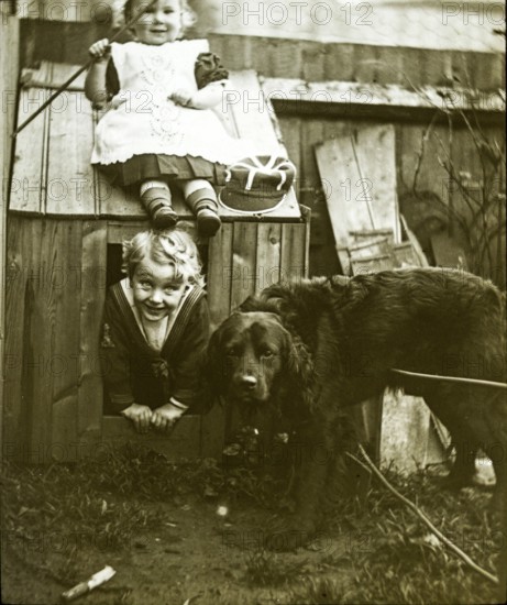 Boy and girl brother and sister playing with dog kennel in garden C 1900-1910, England, UK
