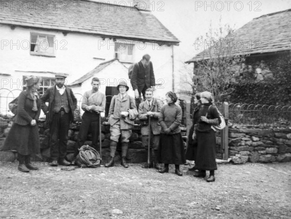 Men and women in mountaineering mountain climbing group standing in fron of cottage, c 1900-1920