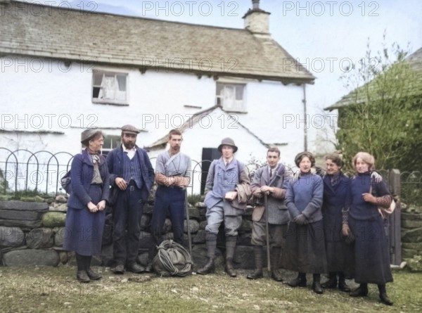 Colourised image of men and women in mountaineering mountain climbing group standing in fron of cottage, c 1900-1920