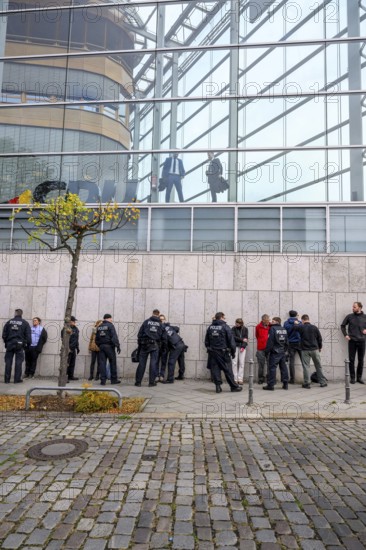 Men look out of the Konrad Adenauer House. Below, police detain activists of the New Generation. After an attempt at a performance by the New Generation to fight corruption in front of the Konrad Adenauer House, the federal headquarters of the CDU. Berlin, 06.10.2025