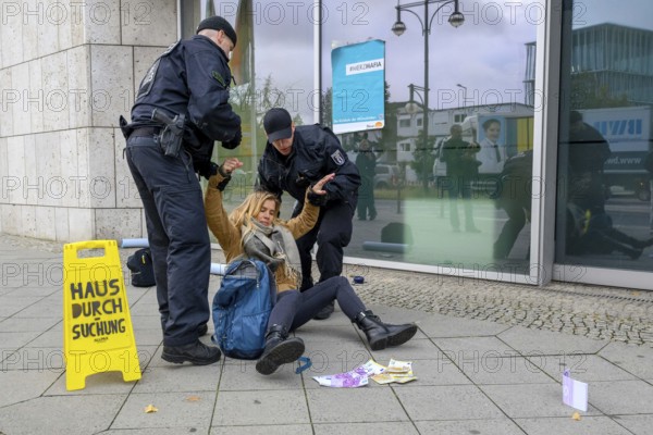 New generation raids the Konrad Adenauer House, the federal headquarters of the CDU, on suspicion of corruption. Police arrest activist. Warning sign with house search. A New Generation poster with #Merzmafia / Return of the #Klimakleber is stuck to the building. Fake banknotes scattered on the floor. Berlin, 06.10.2025