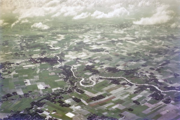 Captioned as 'aerial photo Saigon', meandering river in flat agricultural landscape of paddy fields, Vietnam, south east Asia c 1964
