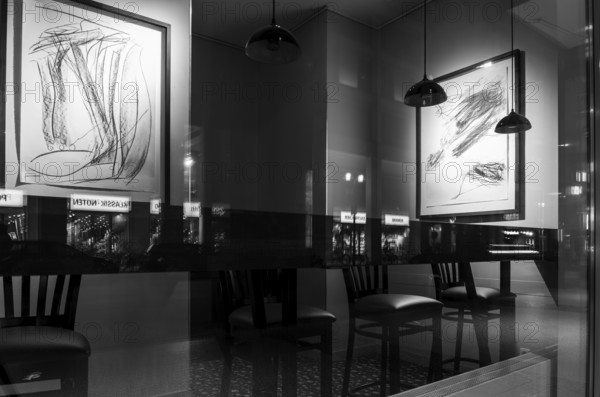 Black and white photograph, urban scene in the evening with reflections of Friedrichstraße in the window pane of a bistro, Berlin, Germany