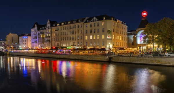 Night photo on the banks of the Spree opposite the Schiffbauerdamm, urban environment with scene locations at the Berliner Ensemble theatre, reflections of the night lighting appear in the water of the Spree, Berlin, Germany