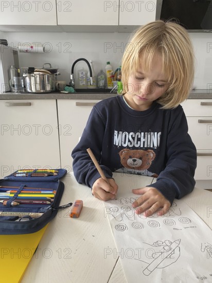 Boy, 6 years old, blond, 1st grade, practises holding the pen correctly, does homework in the kitchen, pencil case, Stuttgart, Baden-Württemberg, Germany